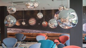 Un área de descanso moderna con lámparas colgantes esféricas únicas y un mural con temática espacial en la pared.