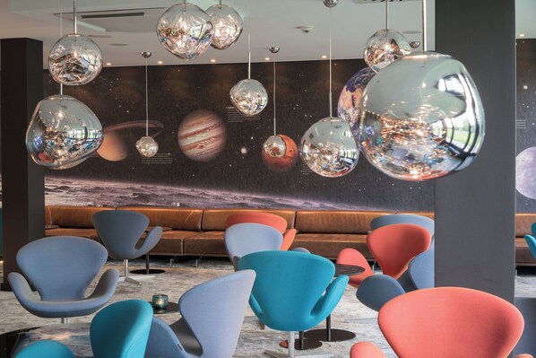 A modern lounge area with unique spherical hanging lights and a space-themed mural on the wall. - Motel One Berlin-Tiergarten (Berlin)