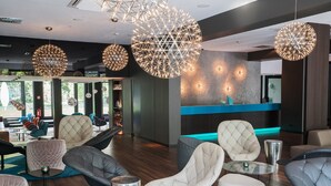 Un espacio lounge moderno con asientos redondos, lámparas de techo geométricas y un mostrador de recepción.