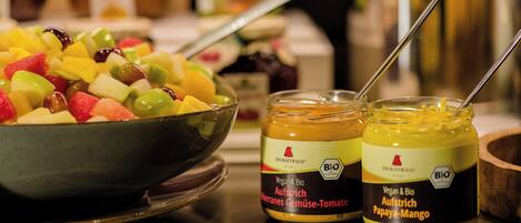 Un saladier de salade de fruits variés et deux pots de condiments végétaliens et biologiques.