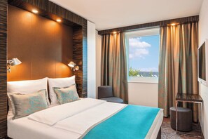 A hotel room with a large bed, a TV, a window with curtains, and a view of the outdoors. - Motel One Berlin-Tiergarten (Berlin)
