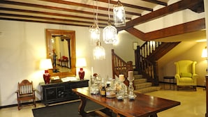 A wooden dining table with candle holders and glassware, a mirror, and a staircase in the background. - Parador de Santillana Altamira (Santillana del Mar)