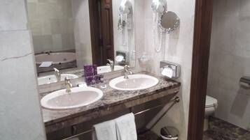 A bathroom with two sinks, a mirror, a hairdryer, and a toilet.