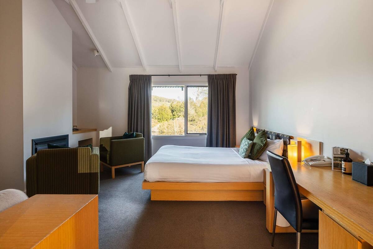 Een hotelkamer met een bed, een bureau, een stoel en uitzicht op de omgeving.