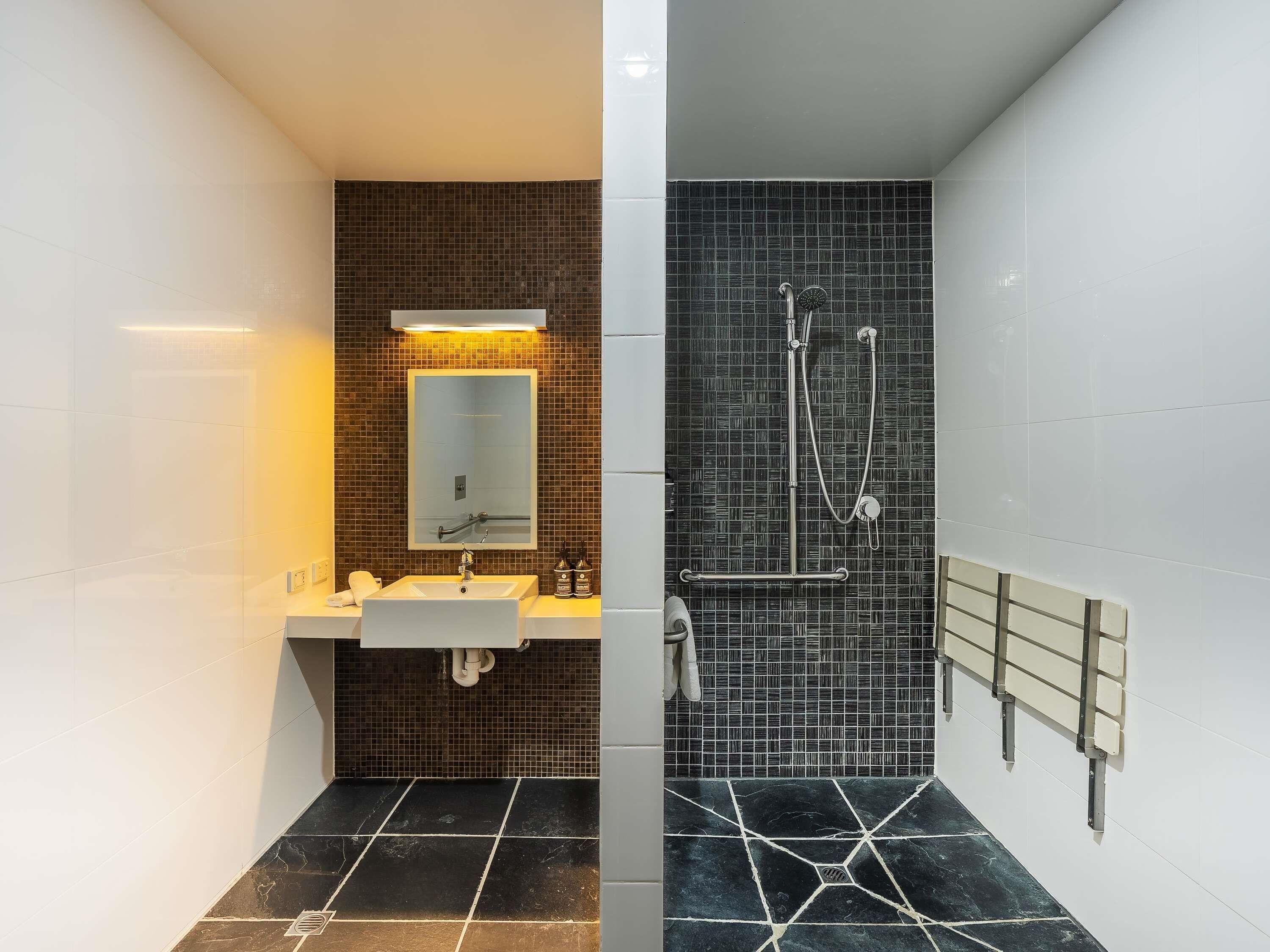 Un baño con lavamanos, espejo y ducha.