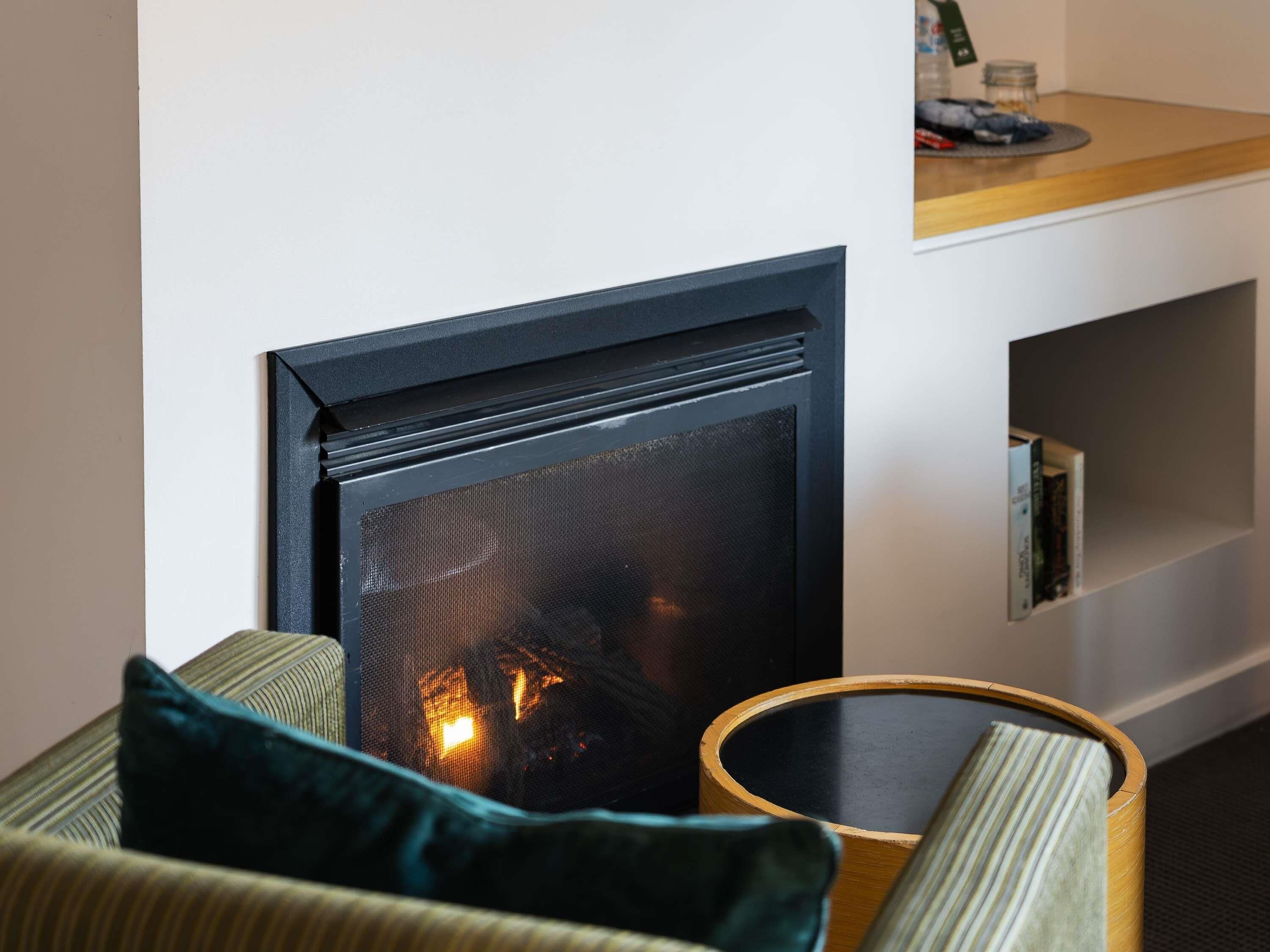 A modern living room with a fireplace, a sofa, and a side table.