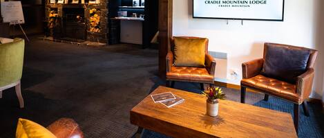 A lobby with leather armchairs, a wooden coffee table, and a fireplace.