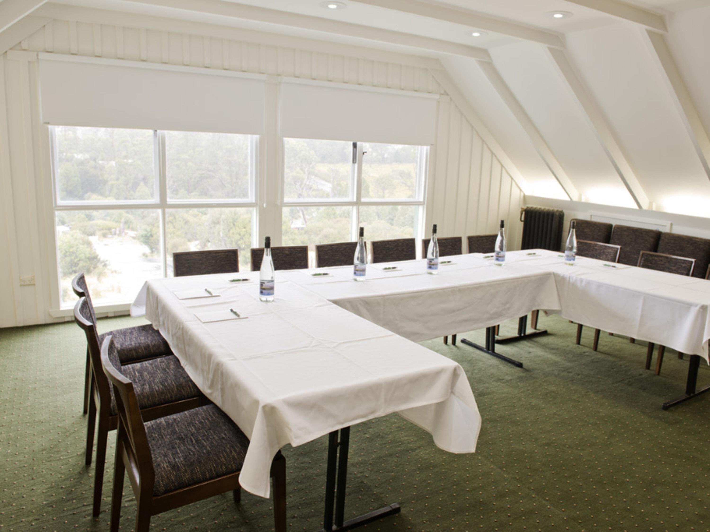 A conference room with a long table, chairs, and large windows.