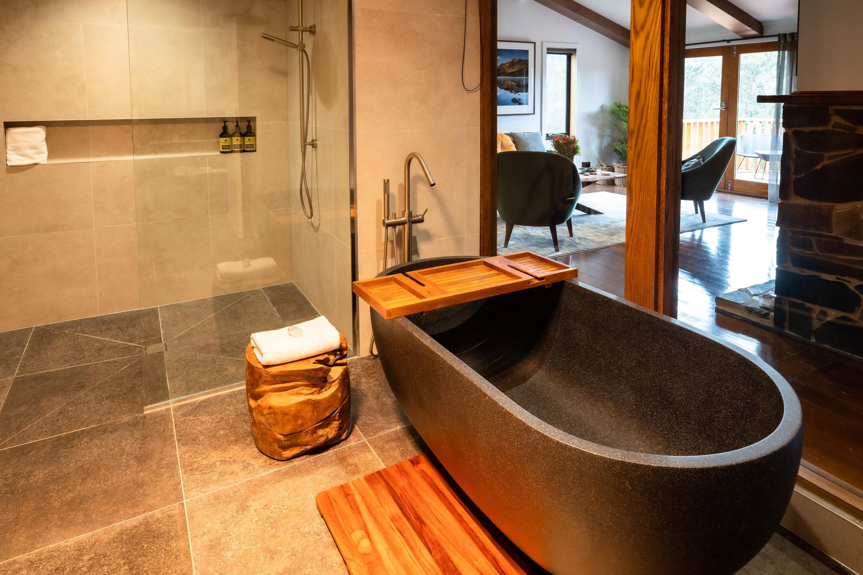 Un bagno moderno con una vasca freestanding, uno sgabello di legno e un portasciugamani.