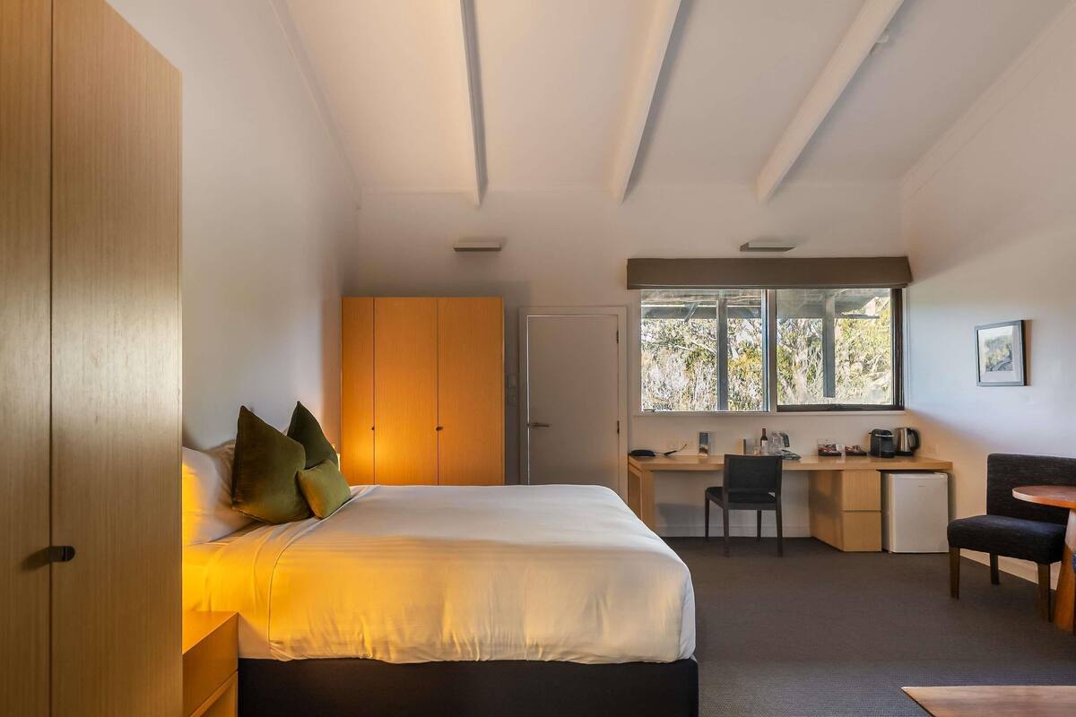 Een slaapkamer met een bed, een bureau en een stoel.