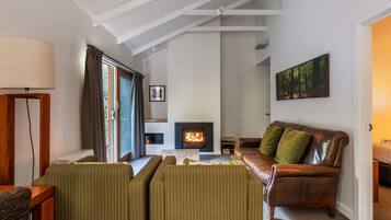 Una sala de estar con chimenea, un sofá, un sillón a rayas, una lámpara y un cuadro en la pared.