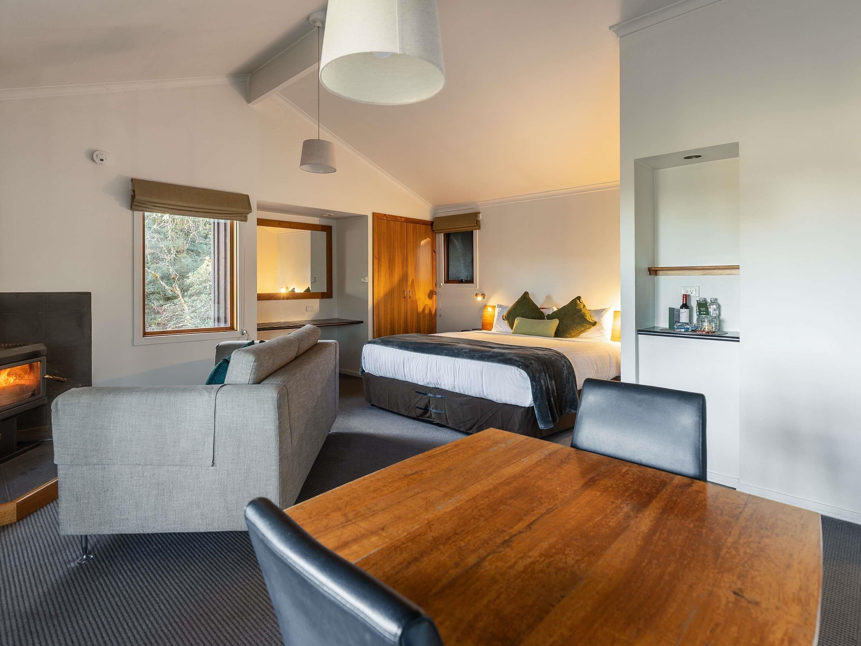 A modern hotel room with a bed, seating area, and a dining table.