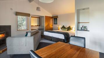 A modern hotel room with a bed, seating area, and a dining table.