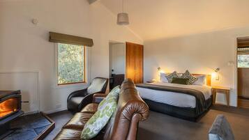 Una habitación acogedora con chimenea, cama, sofá y ventana con vistas al verdor.
