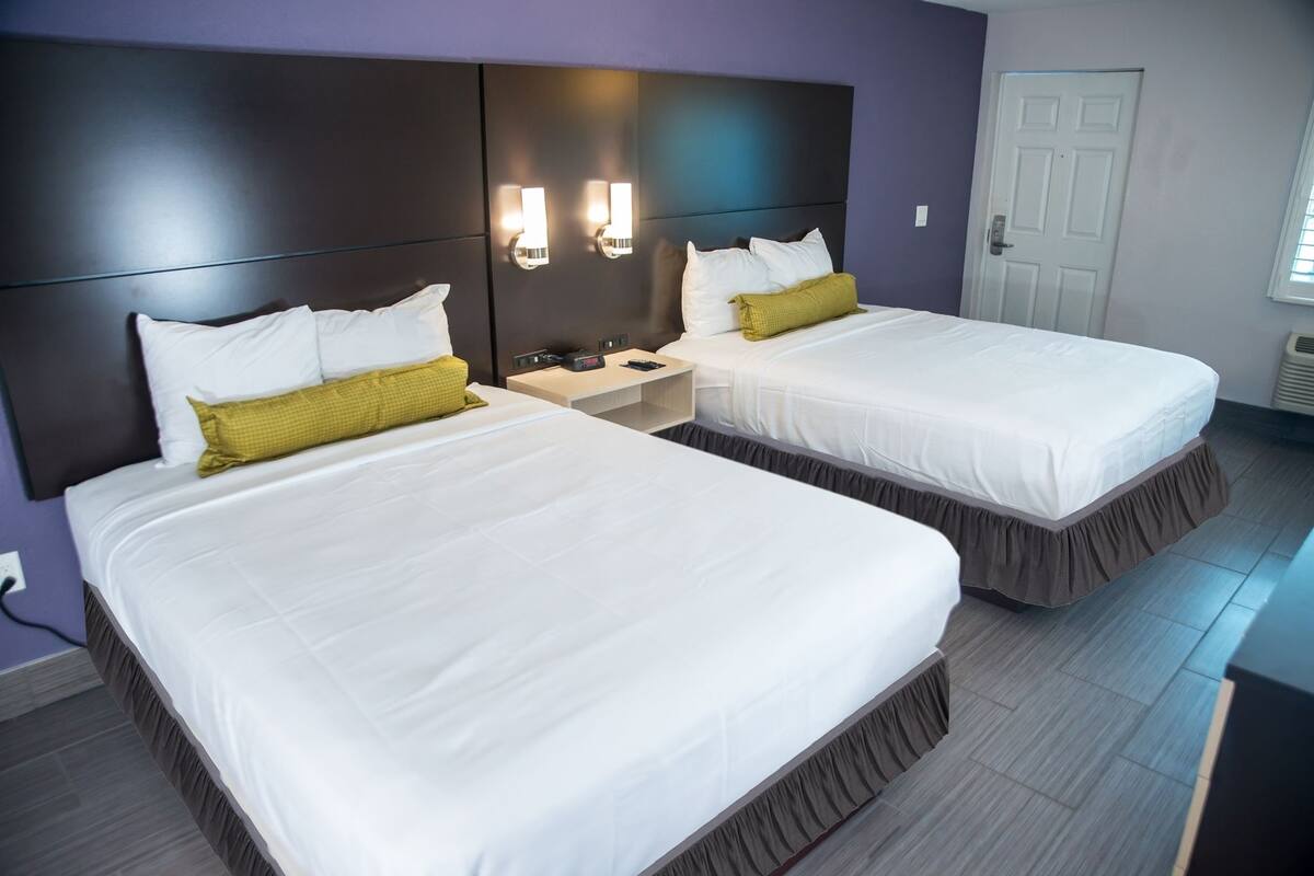 A hotel room with two beds, a nightstand, and a door.