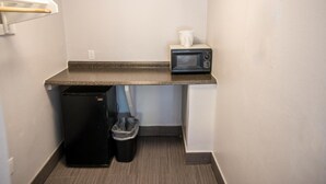 A small kitchenette with a microwave, a trash bin, and a coffee maker on the countertop. - Atlantic Inn (Indialantic)