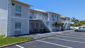 A multi-story hotel with a white exterior, a balcony on the second floor, and a staircase leading to the third floor. - Atlantic Inn (Indialantic)