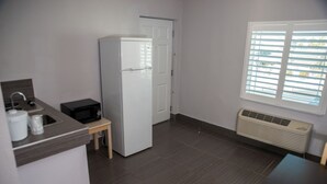 A compact kitchen with a refrigerator, microwave, and sink. - Atlantic Inn (Indialantic)