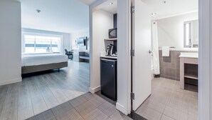 A modern hotel room with a bed, a small kitchenette, and a bathroom with a mirror and sink. - Holiday Inn Express Hotel Saint - Hyacinthe by IHG (Saint Hyacinthe)