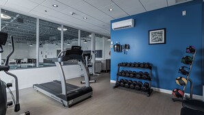 Un gimnasio con cintas de correr, mancuernas y pelotas de ejercicio.