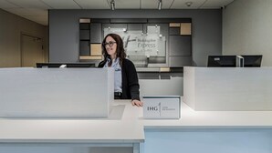 Un mostrador de recepción con un cartel de Holiday Inn Express & Suites y un cartel de IHG One Rewards.