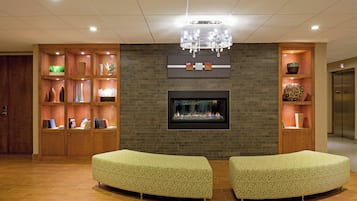 Un vestíbulo con chimenea, dos sofás, estanterías de madera con objetos decorativos y un candelabro.