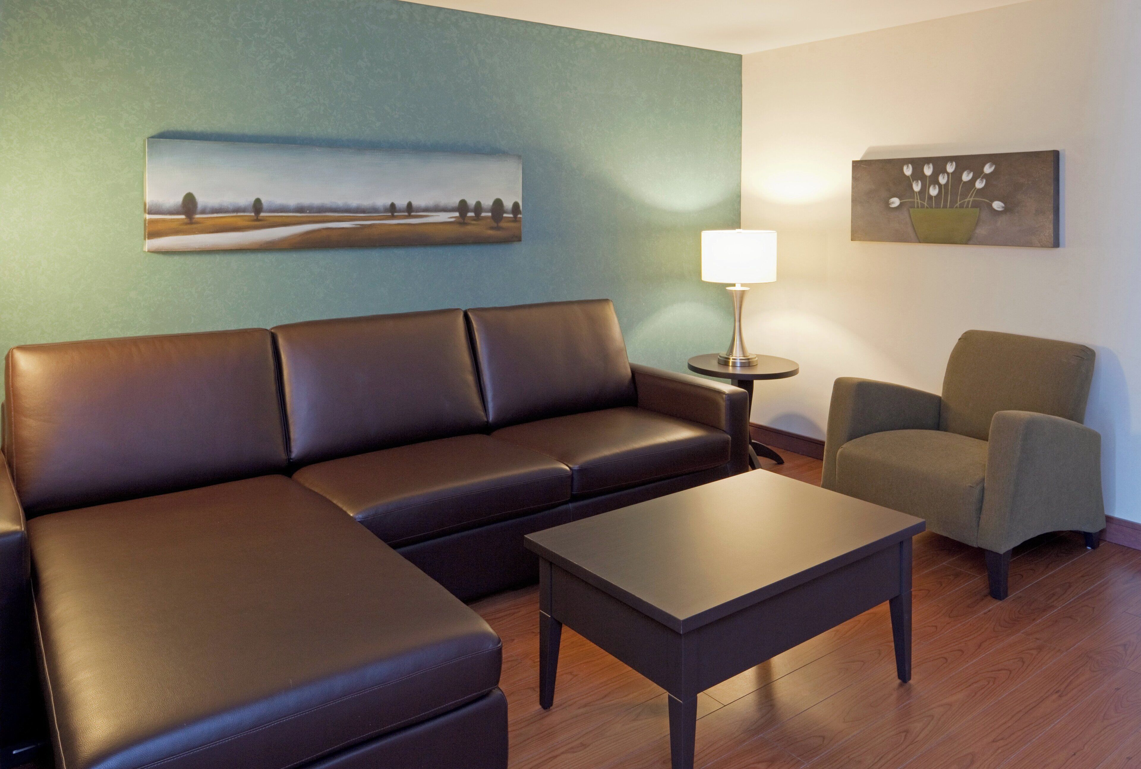 A modern living room with a sectional sofa, a small table, and two armchairs.