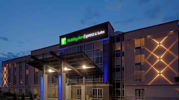 Edificio de Holiday Inn Express & Suites con entrada cubierta y cielo despejado.