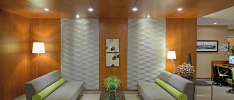 A modern lobby with two sofas, a coffee table, and a decorative plant.