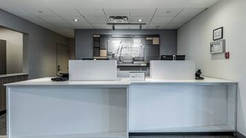 Un comptoir d’accueil au design moderne, un écran numérique et une enseigne pour Holiday Inn Express Suites.