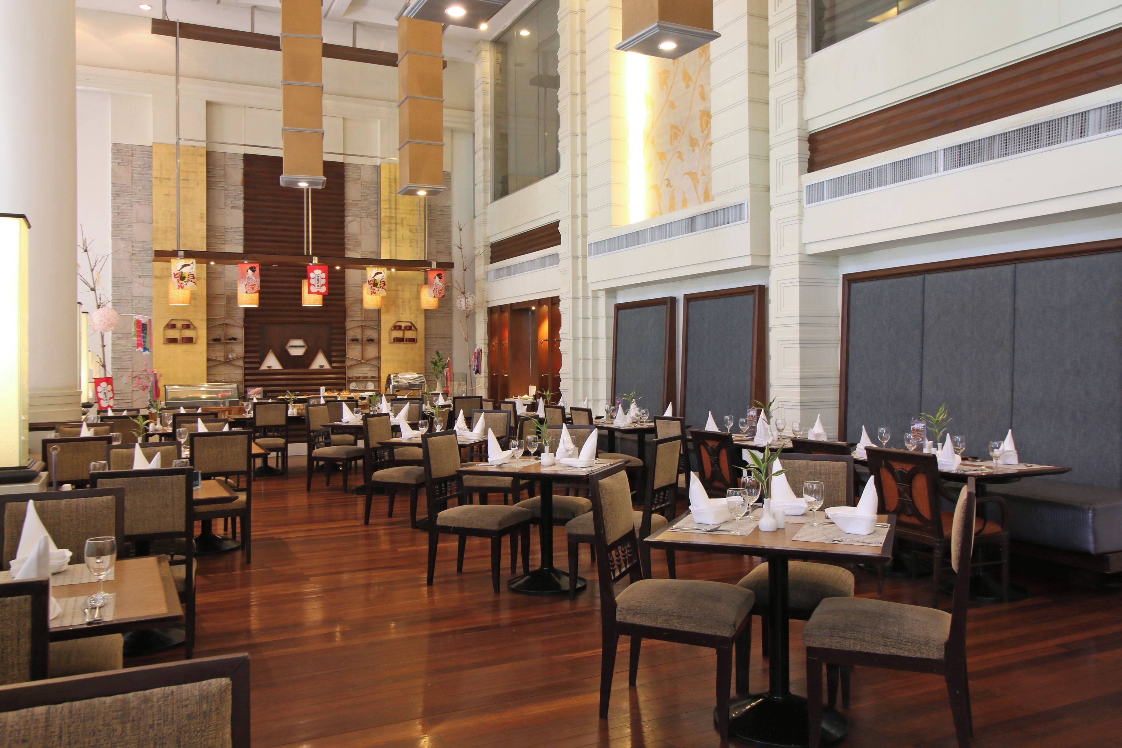 A spacious restaurant with high ceilings, multiple dining tables, and chairs arranged for guests.