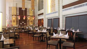 A spacious restaurant with high ceilings, multiple dining tables, and chairs arranged for guests.