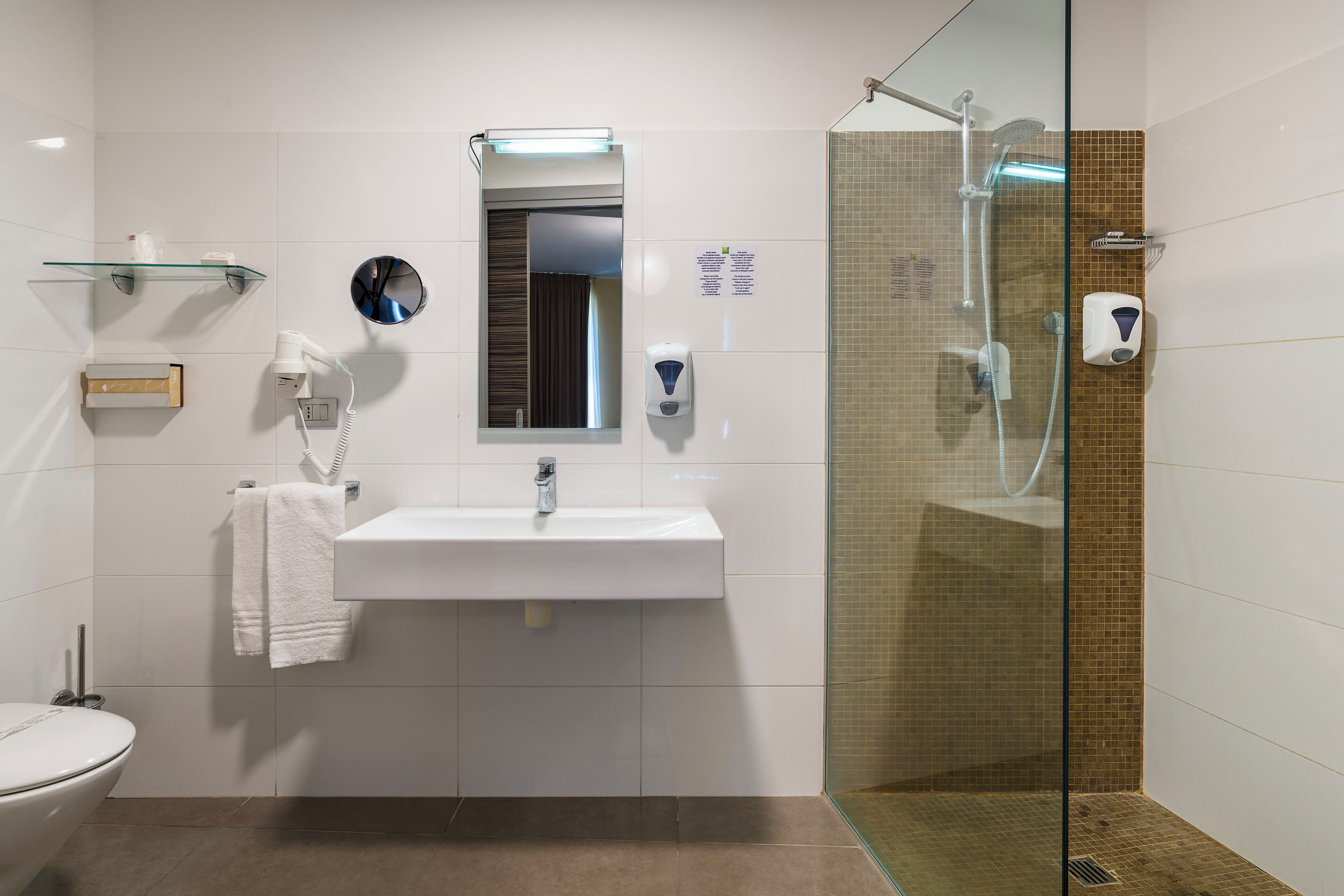 A bathroom with a glass-enclosed shower, a white sink, a mirror, and a towel rack.