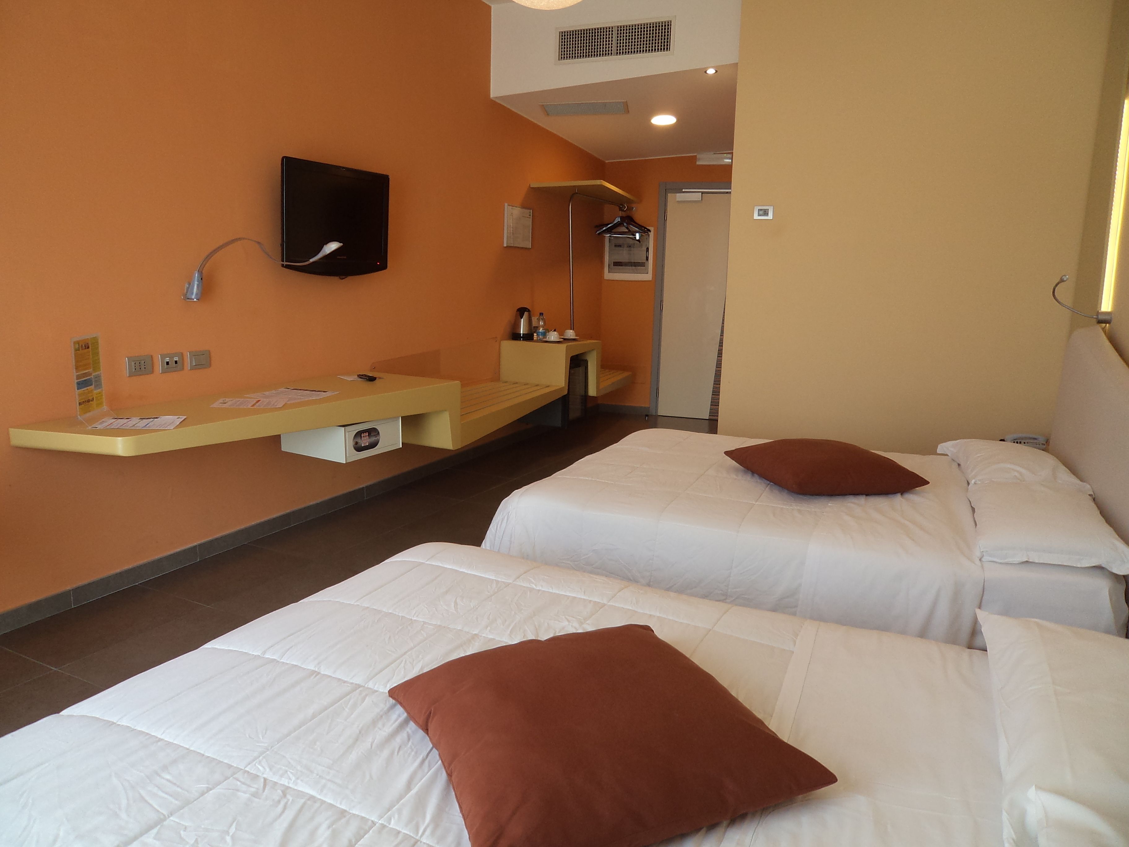 Une chambre d’hôtel avec deux lits, un petit bureau doté d’un téléviseur à écran plat, un mini-réfrigérateur et un porte-serviettes.