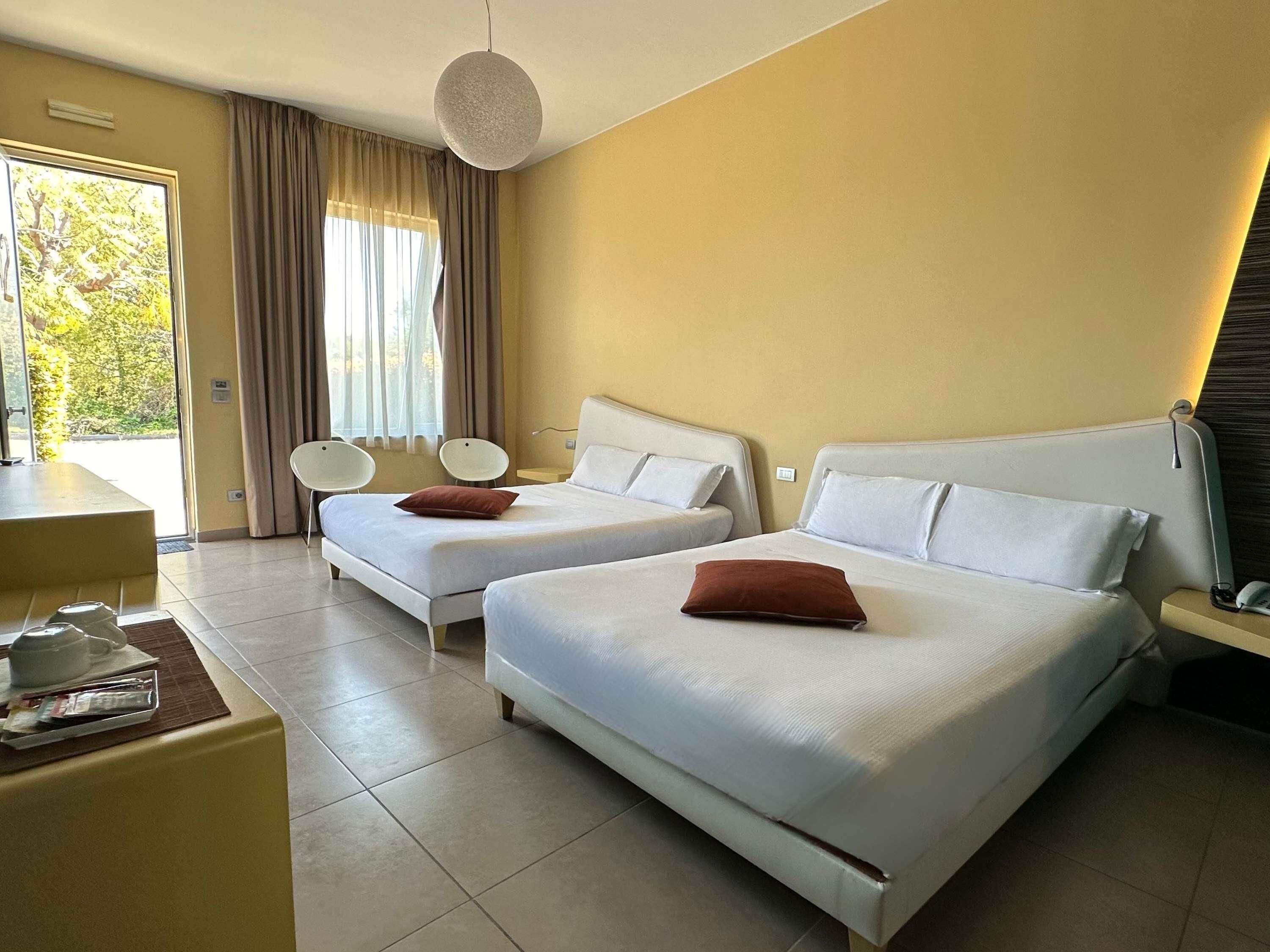 A hotel room with two beds, a desk, and a chair.