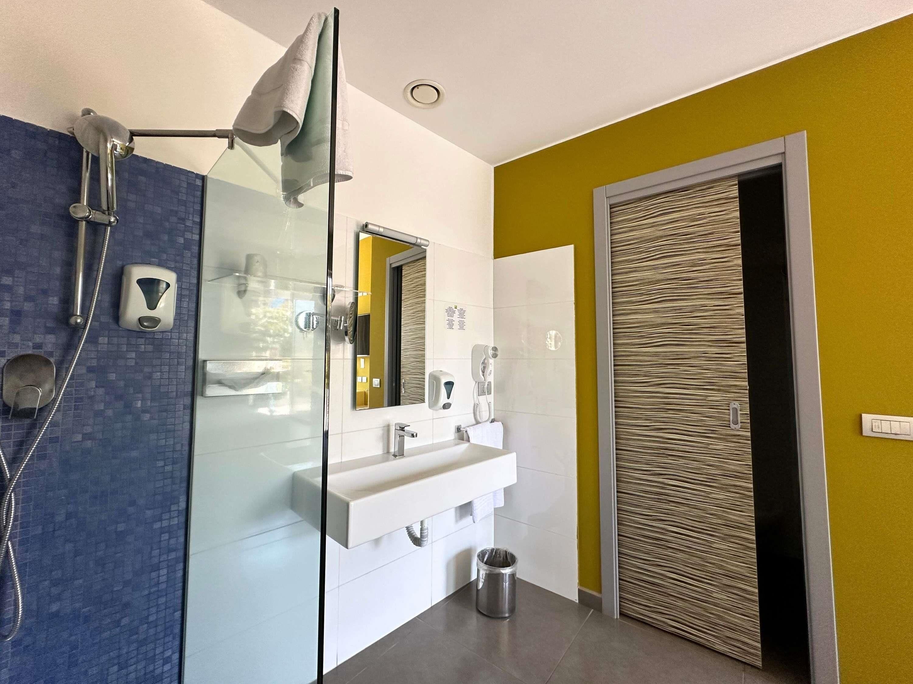 Une salle de bain moderne avec une douche à parois de verre, un lavabo blanc et un miroir.