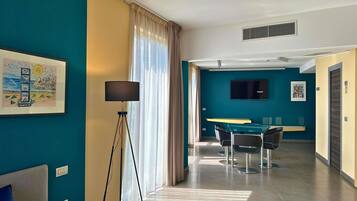 Una habitación de hotel moderna con cama, escritorio, silla, televisor y un ventanal con cortinas.