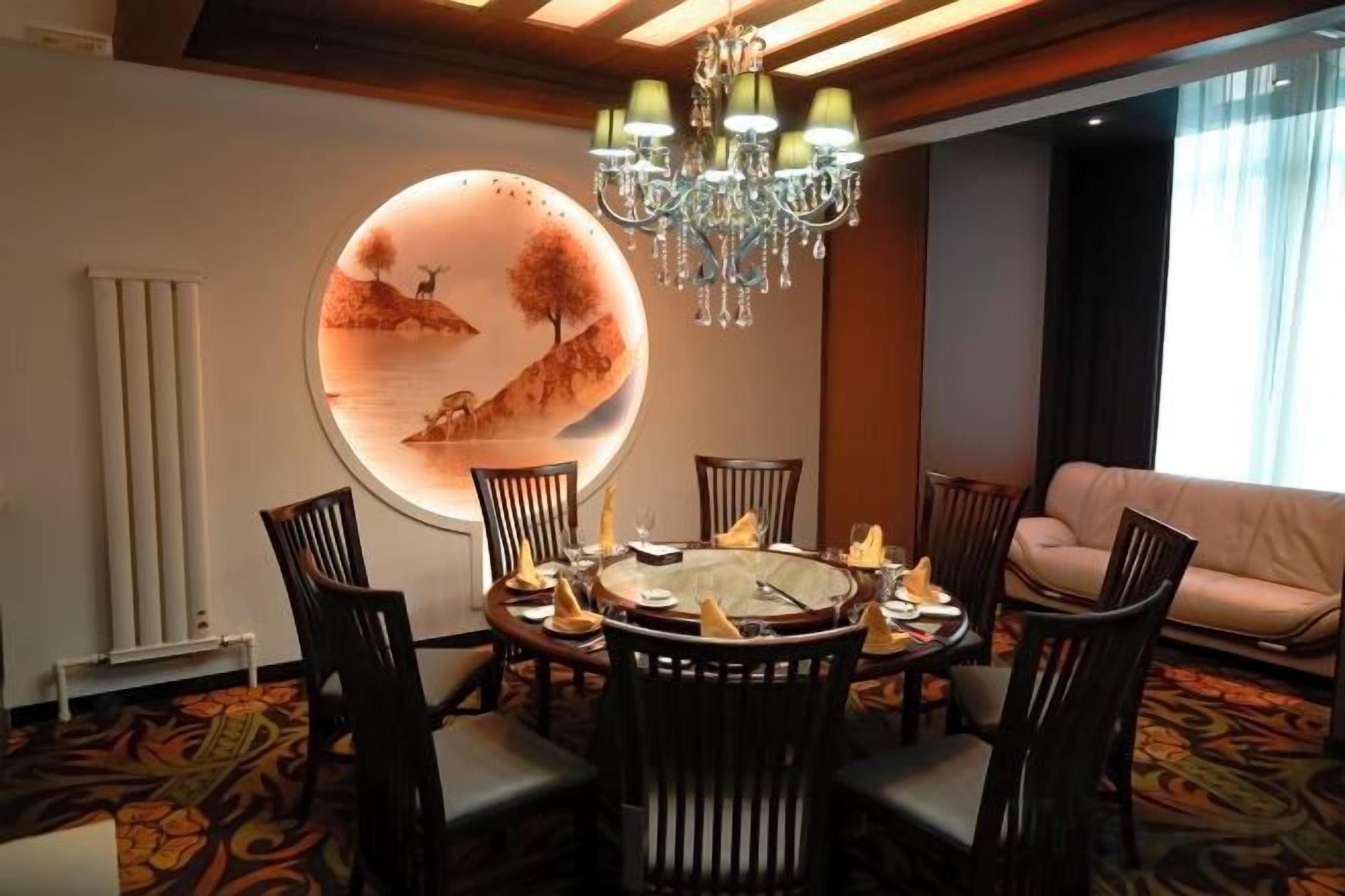 A dining area with a round table, chairs, and a chandelier.