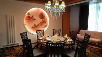 A dining area with a round table, chairs, and a chandelier.