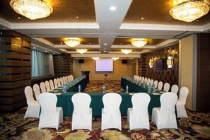 A conference room with a long table, white chairs, and chandeliers. - Baotou Hotel State Guest Building (Baotou)