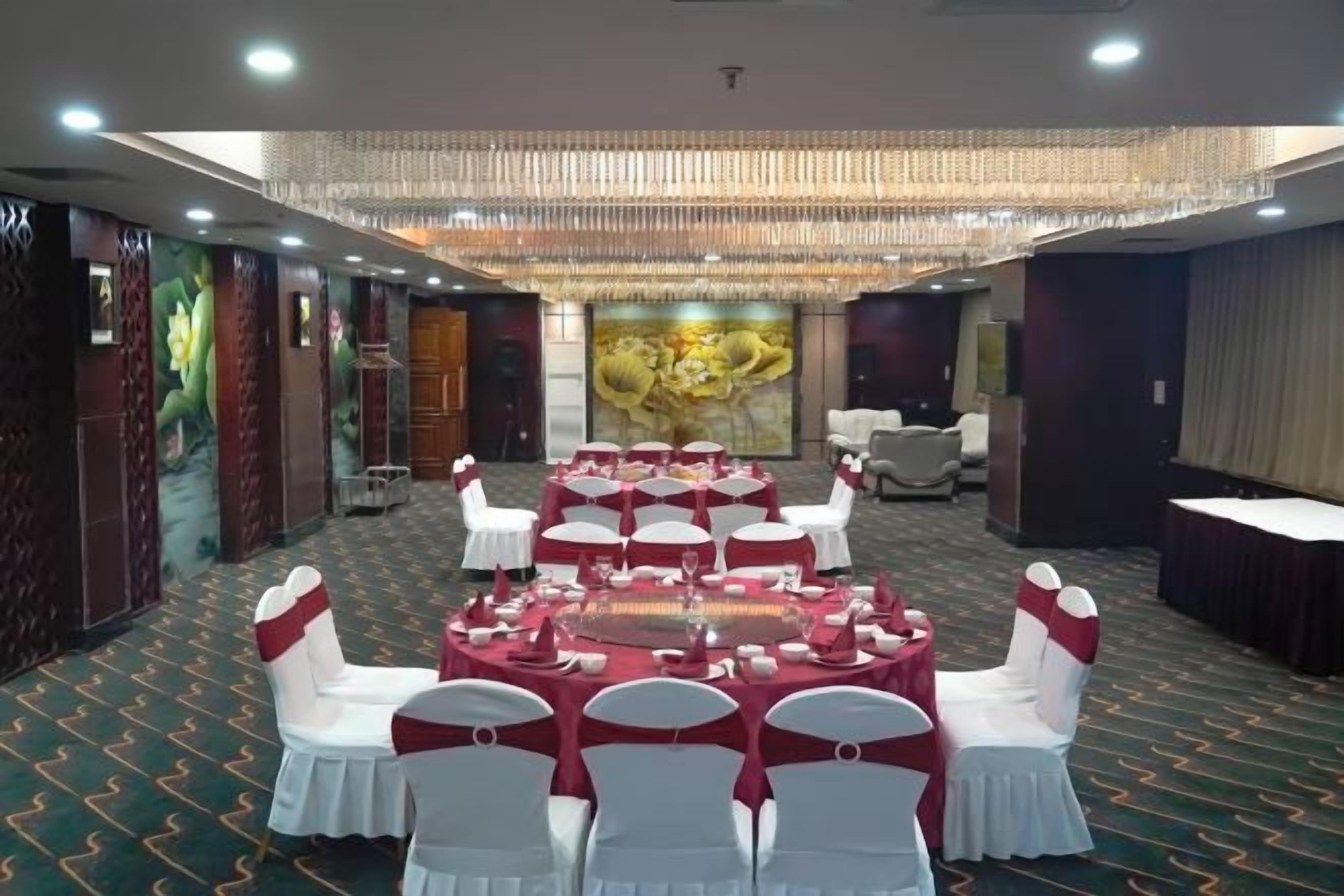 A banquet hall with round tables, white chairs, and a chandelier.