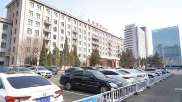 A multi-story hotel with a row of parked cars in front.
