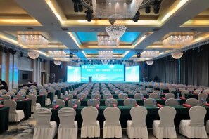 A conference room with rows of tables, chairs, and a stage with a large screen. - Baotou Hotel State Guest Building (Baotou)