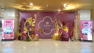 A reception area with a floral arrangement, a large sign with text, and a digital display.