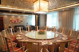 Una mesa de comedor redonda con sillas, una araña y un centro de mesa floral.
