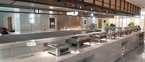 A buffet setup with multiple serving stations, a kitchen area, and a seating area with tables.