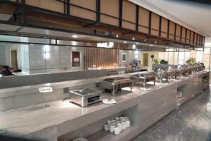 A buffet setup with multiple serving stations, a kitchen area, and a seating area with tables. - Baotou Hotel State Guest Building (Baotou)