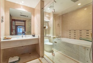 A modern bathroom with a glass-enclosed shower, a large mirror, and a marble countertop.