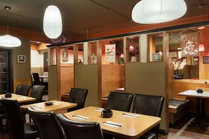 Ein Restaurantinneres mit Holztischen und schwarzen Ledersesseln, mit Papierslaternen und traditioneller Einrichtung.