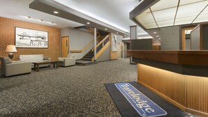 Un vestíbulo de hotel con recepción, escalera y zona de estar.
